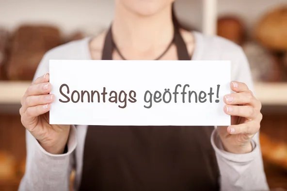 Frau hält Schild mit Sonntags geöffnet hoch