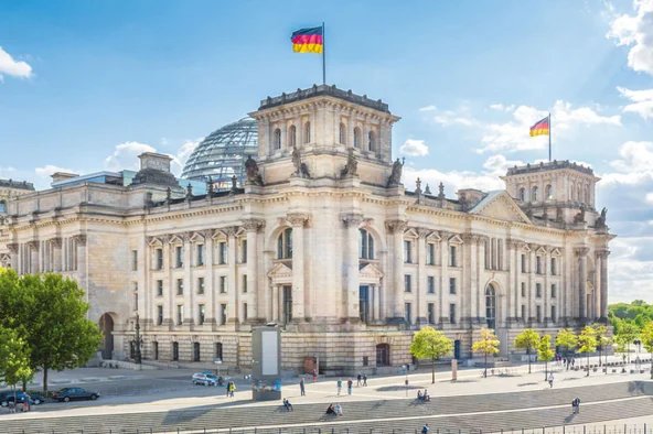 Der Deutsche Bundestag mit wehender Deutschlandfahne in Berlin – Symbol der politischen Entscheidungen, die auch für Betriebsräte wichtige arbeitsrechtliche Veränderungen bedeuten können.