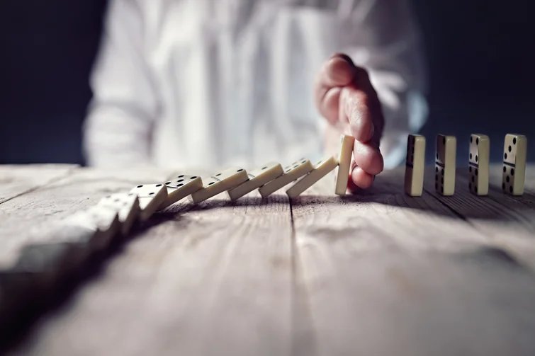 Hand stoppt fallende Dominos