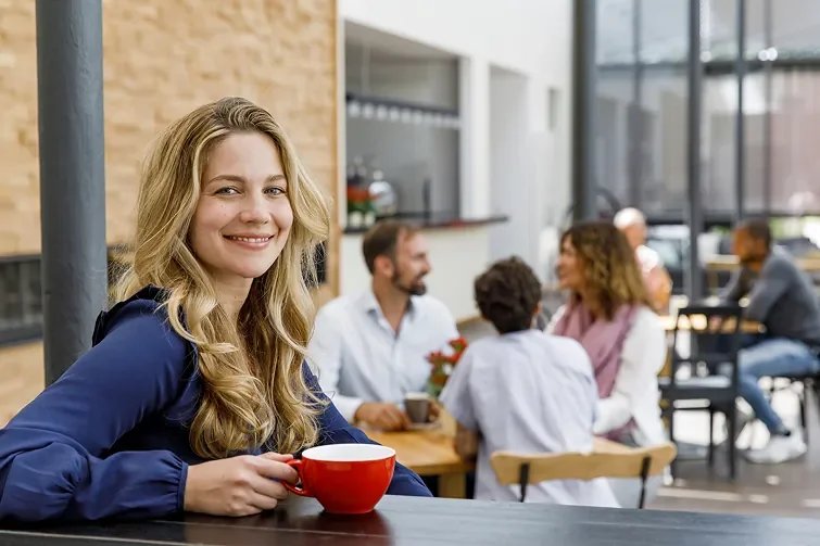 Person sitzt mit einem Café in der Küche, da sie Teilzeit hat.