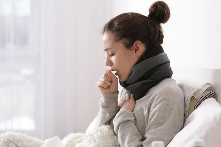Frau hustet und liegt im Bett