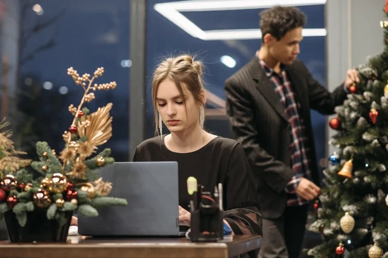 Frau sitzt am Laptop vor einem Weihnachtsbaum