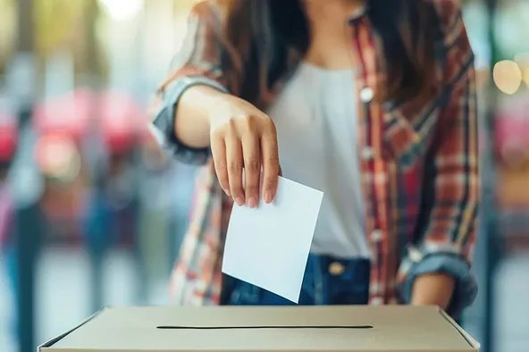 Frau wirft ihren Stimmzettel in eine Wahlurne