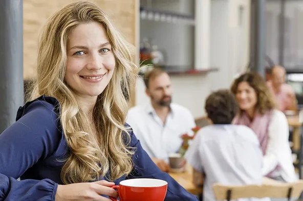 Frau feiert mit einem Kaffee in der Hand ihren Amtszeit eintritt