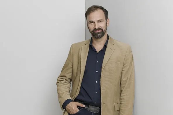 Mitglied des Wirtschaftsausschuss steht vor einer grauen Wand