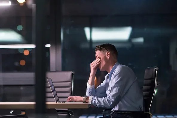Ein Mann ist bei der Arbeit überlastet und steht kurz vor einem Burnout