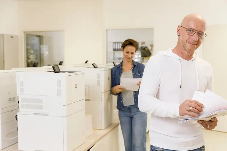 Person entnimmt dem Drucker ein Blatt Papier